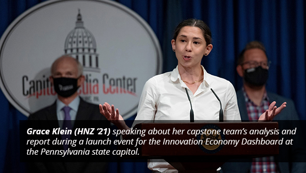 Grace Klein from Heinz College speaking at a podium in Harrisburg with professor Rick Stafford standing behind